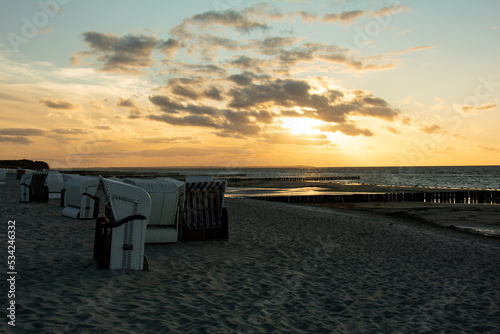 Sunset over the sea with beach chairs on the sandy beach