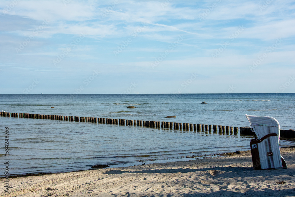 Sand Beach with a wicker beach basket at the Baltic Sea with groynes in the sea Sand Beach with a wicker beach basket at the Baltic Sea with groynes in the sea