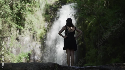 caucasian woman observes the waterfall over the rocks in kaiate falls. Slow motion photo