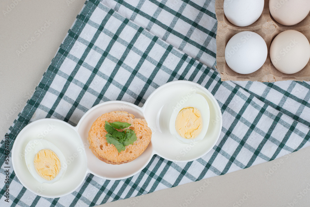 Fresh chicken white uncooked eggs with boiled egg on tablecloth Fresh chicken white uncooked eggs with boiled egg on tablecloth