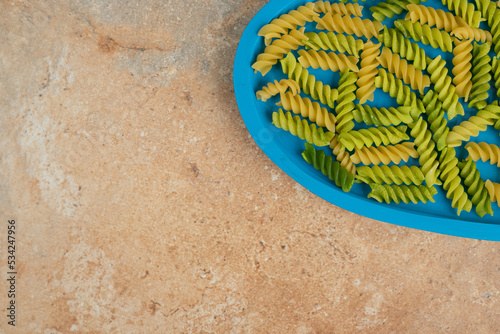 Unprepared spiral macaroni on blue plate