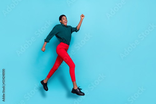 Photo of attractive cute androgynous human wear green shirt hurrying jumping high empty space isolated blue color background