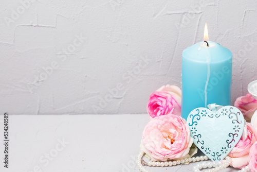 Summer   still life  greeting card. Decorative blue hert, canddle and tender  pink roses on grey textured background. Place for text.