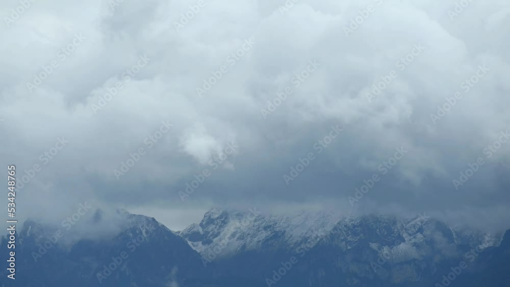 Landscape of mountain, sky and clouds. Time lapse of dark clouds and mist over snowcapped mountains. Dramatic sky.