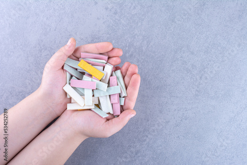 Hands full of bubblegum strips on marble background