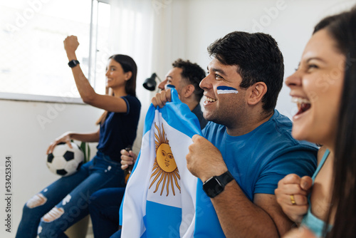 Football fans friends watching Argentina national team in live soccer match on TV at home photo