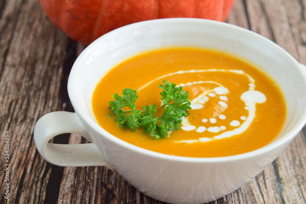 Pumpkin soup with coconut milk with parsley. Wooden background Pumpkin soup with coconut milk with parsley. Wooden background