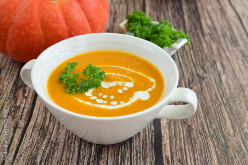Pumpkin soup with coconut milk with parsley. Wooden background