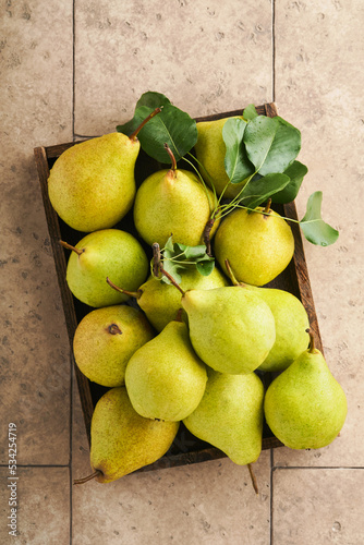 Pears. Fresh sweet organic pears with leaves in wooden box or basket on old stone tile background. Autumn harvest of fruits. Top view. Food background.