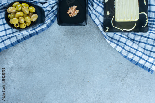 Breakfast with pitless olives, cream, honey and cheese on a towel on marble background photo