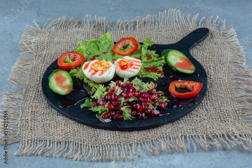 Serving tray reakfast made of boiled eggs, cucumber and pepper slices and pomegranate salad on marble background photo