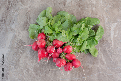 Fresh bunch of red turnips and turnip leaves on marble background