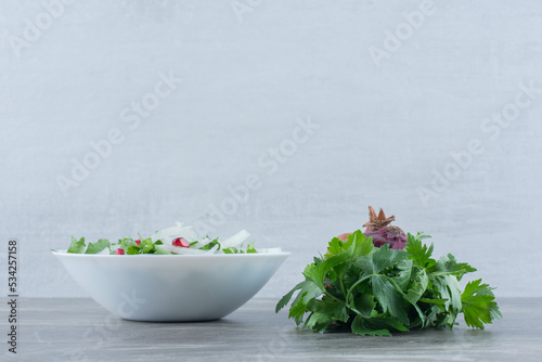 Cilantro, onion and pomegranate made into a salad in a bowl on marble background