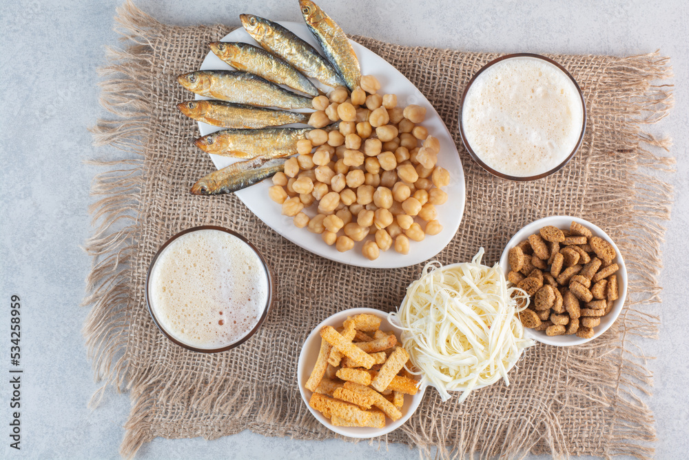 Two glasses of beer with fish and breadsticks on sackcloth background Two glasses of beer with fish and breadsticks on sackcloth background