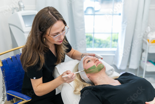 Woman applying a green tea skin care facial at a local spa
