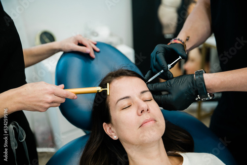 A woman getting botulinum toxin or fillers on her forehead and face by a doctor and nurse practitioner