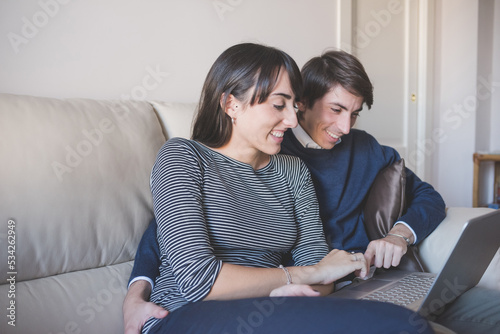 Young couple indoors using computer together