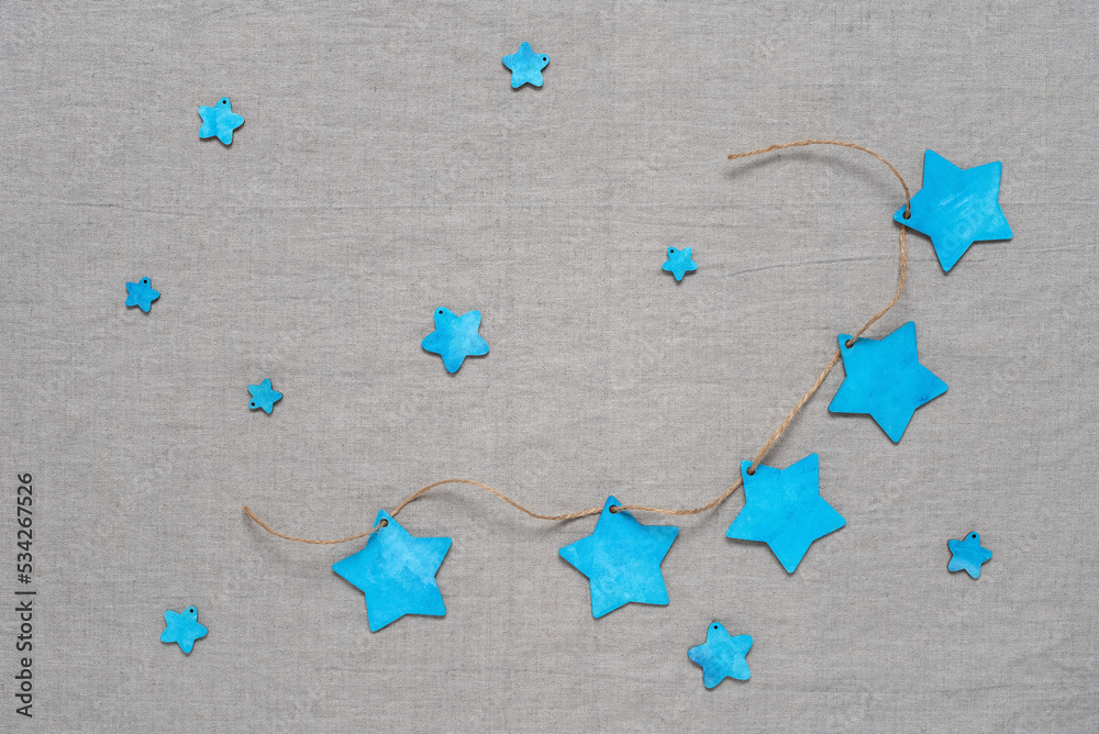 Christmas background with blue wooden stars. Gray linen textile background. Top view, flat lay.