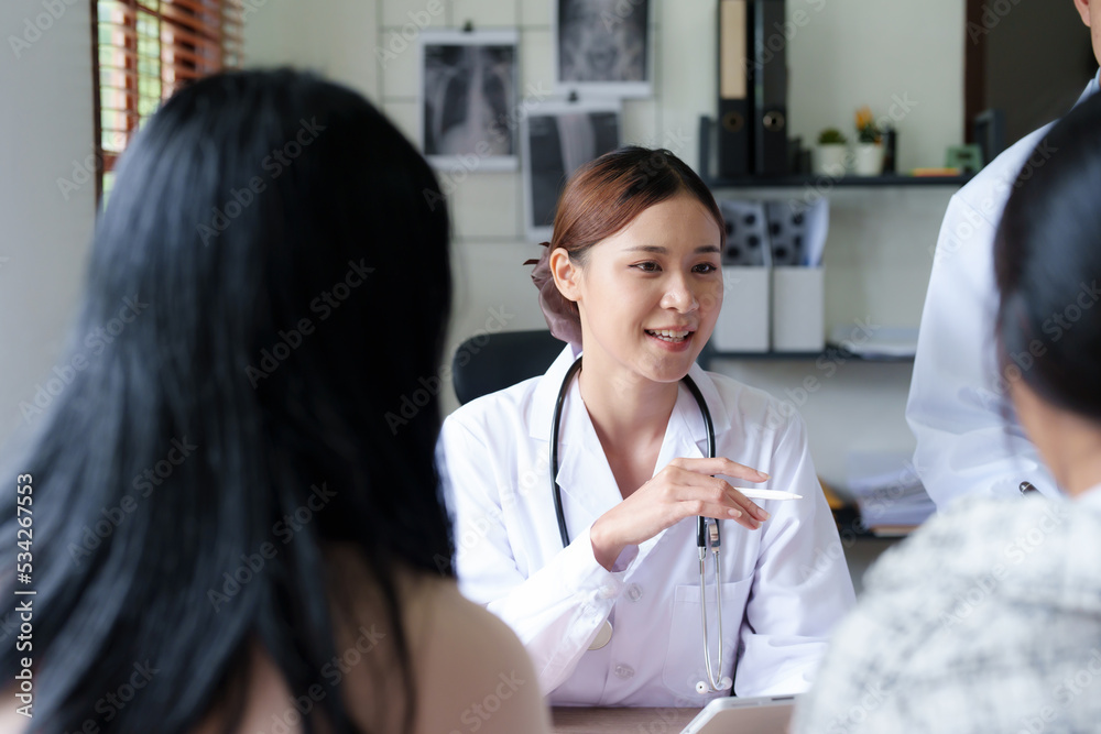 Portrait of a doctor advising clients on health issues holding a tablet to work and talking to patients who come to treatment Portrait of a doctor advising clients on health issues holding a tablet to work and talking to patients who come to treatment