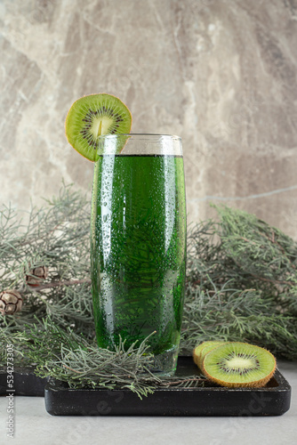 Glass of green juice with kiwi slices and pine branch photo