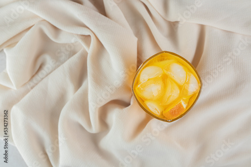 Bild auf Leinwand A glass of orange juice with ice cubes on sateen cloth