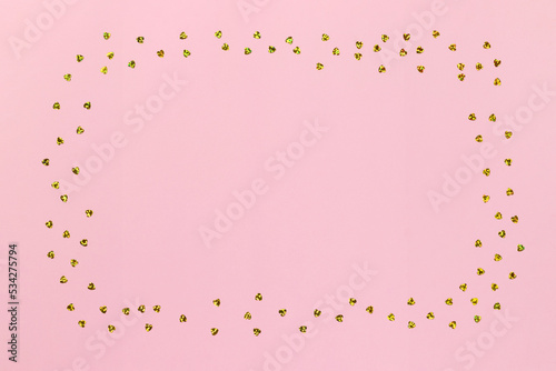 Pink background with golden glitter confetti hearts with copy space