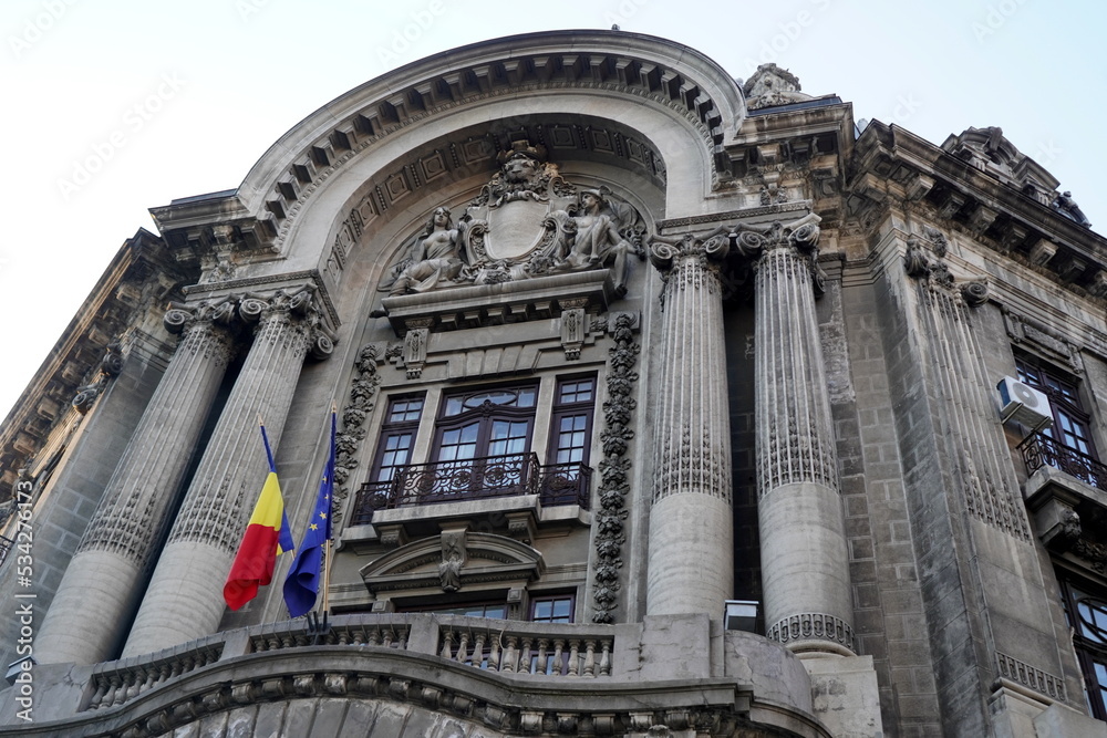 Facade of old Palace of Chamber of Commerce and Industry in center of Bucharest. Old beautiful classical building facade with allegoric stone sculpture on semicircular pediment and ionic columns.