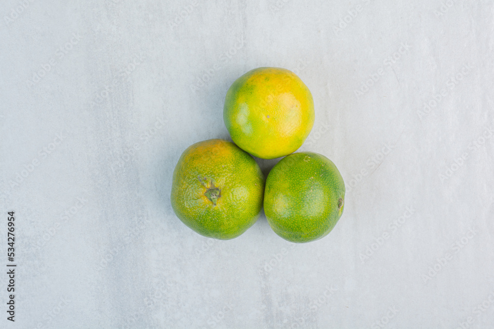Three unpeeled tangerines on stone background Three unpeeled tangerines on stone background