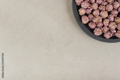 Purlple, flavored popcorn in a small, black tray on marble background photo