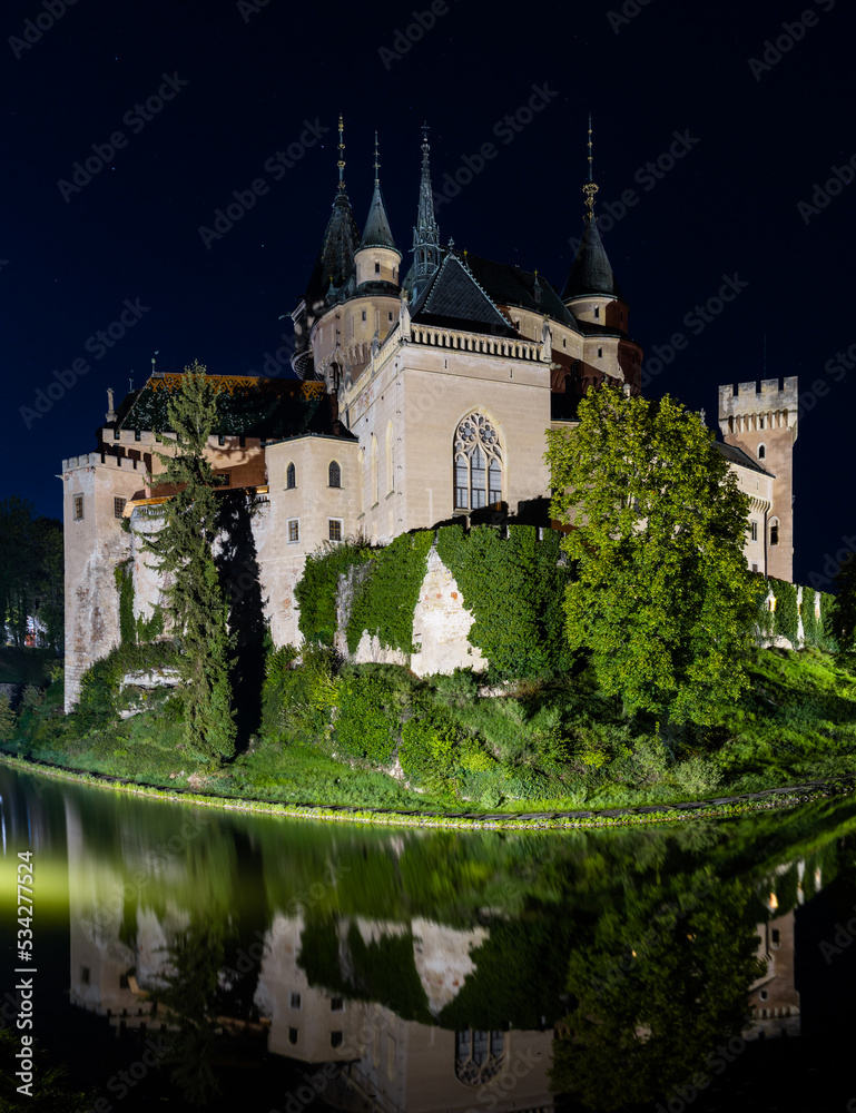 view of the Bojnice Castle with reflections in the water at night