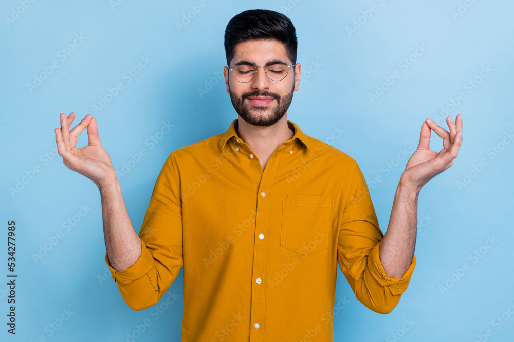 Naklejka premium Photo of peaceful carefree handsome man dressed yellow shirt closed eyes hands fingers meditate isolated on blue color background