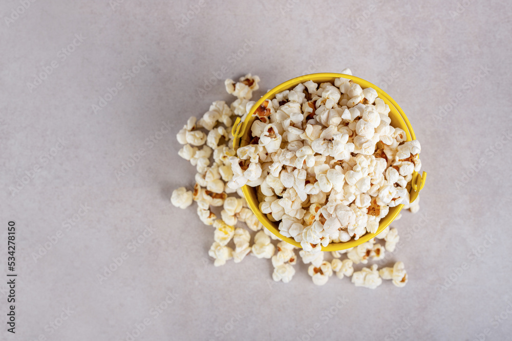 Popcorn overflowing from a small bowl on marble background Popcorn overflowing from a small bowl on marble background