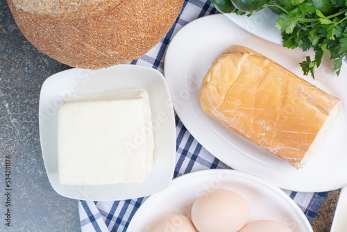 Boiled eggs and various cheese on plates photo