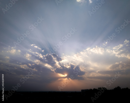 Beautiful blue sky, sunset scenery view, nature photography, sunrays shining behind clouds, natural background