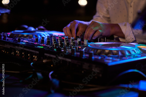 an unrecognizable person playing music at a party from a mixing console
