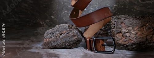 leather belt on a dark background with bark and natural stone on the background. levitation. stylish details of men's clothing. photo