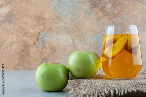 Glass of juice and fresh apples on burlap photo