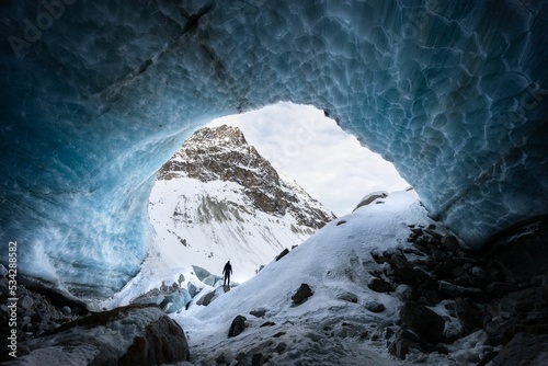 Ice cave exploration with a silhouette of a hiker in Arolla glacier, Valais Switzerland photo
