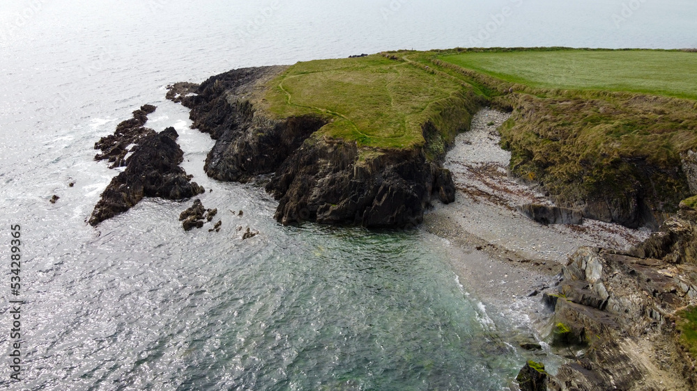 Nature on the Wild Atlantic Way, the south of Ireland. Picturesque coastal cliffs on the shore of the Celtic Sea.  Rocky hills covered with thick green grass. Northern European landscape. Aerial photo