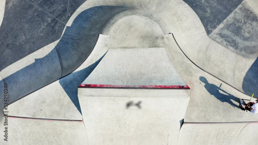 Aerial drone Skate Park concrete bowl shot, large skatepark zone, kick scooter skateboard riders training, skateboarding playground.