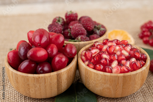 Bowls of pomegranate  raspberries and hips on textile background