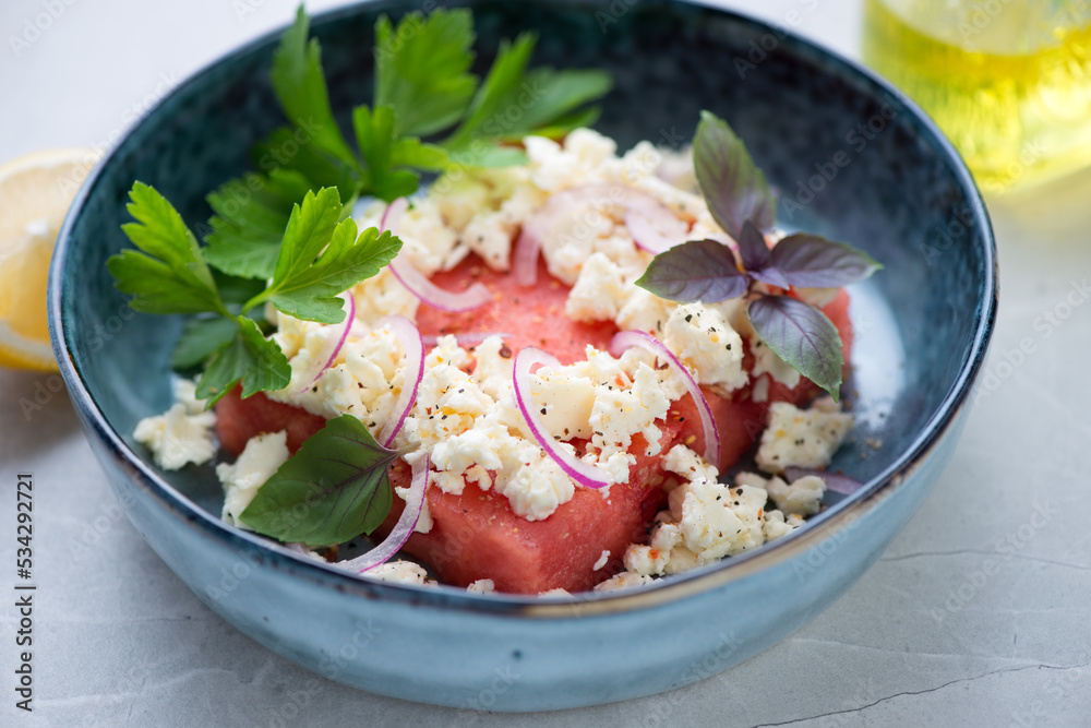 Close-up of watermelon served with feta cheese, fresh parsley and basil in a blue bowl, selective focus, horizontal shot Close-up of watermelon served with feta cheese, fresh parsley and basil in a blue bowl, selective focus, horizontal shot