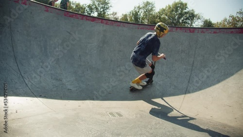 Man making trick on kick scooter in concrete bowl, air extreme in skate park, grab and barspin jump, young skater boy.  photo