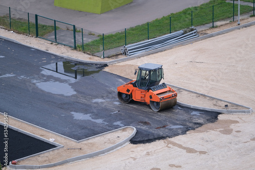 Orange small asphalt paver machine laying asphalt road, top view