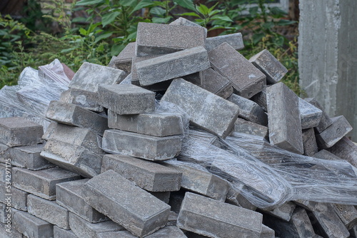 a pile of gray brick paving slabs and white cellophane packaging on the street