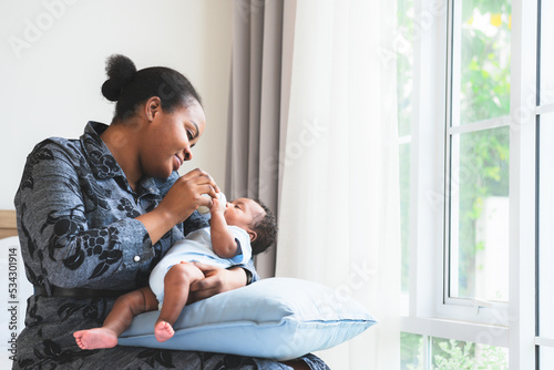 an African mother feeding milk from bottle milk to her 2-month-old baby newborn son, to African family and food for infant concept.