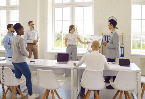 Colleagues in office work discuss presentation on whiteboard and explain work strategy. Business people during brainstorming session working process share ideas. Teamwork and cooperation concept. photo