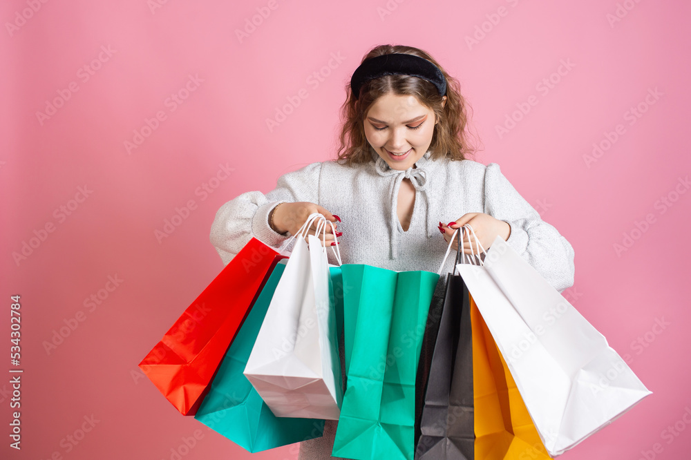 Cute girl holding bright paper bags and watching shopping Cute girl holding bright paper bags and watching shopping