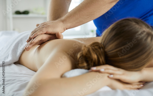 Close up of masseur work with female client relieve backache or muscle strain. Physiotherapist massage woman patient back help with rehabilitation in clinic or salon. Recovery and wellness concept.