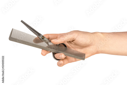 A woman's hand holds a comb and thinning scissors. Isolated on white background. Barber tools
